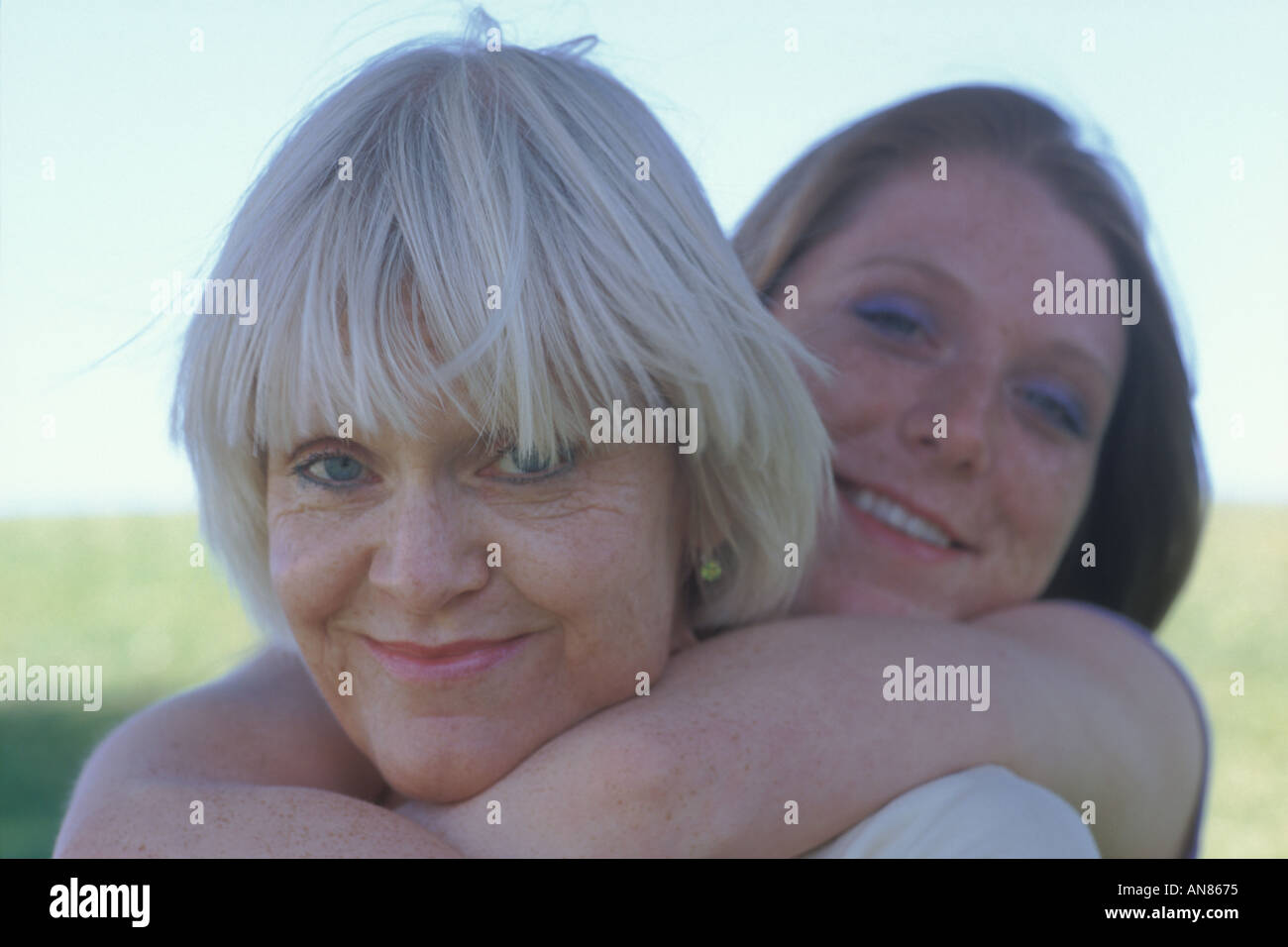 Portrait of 57 year old Caucasian woman and 22 year old daughter hugging her mother from behind Stock Photo