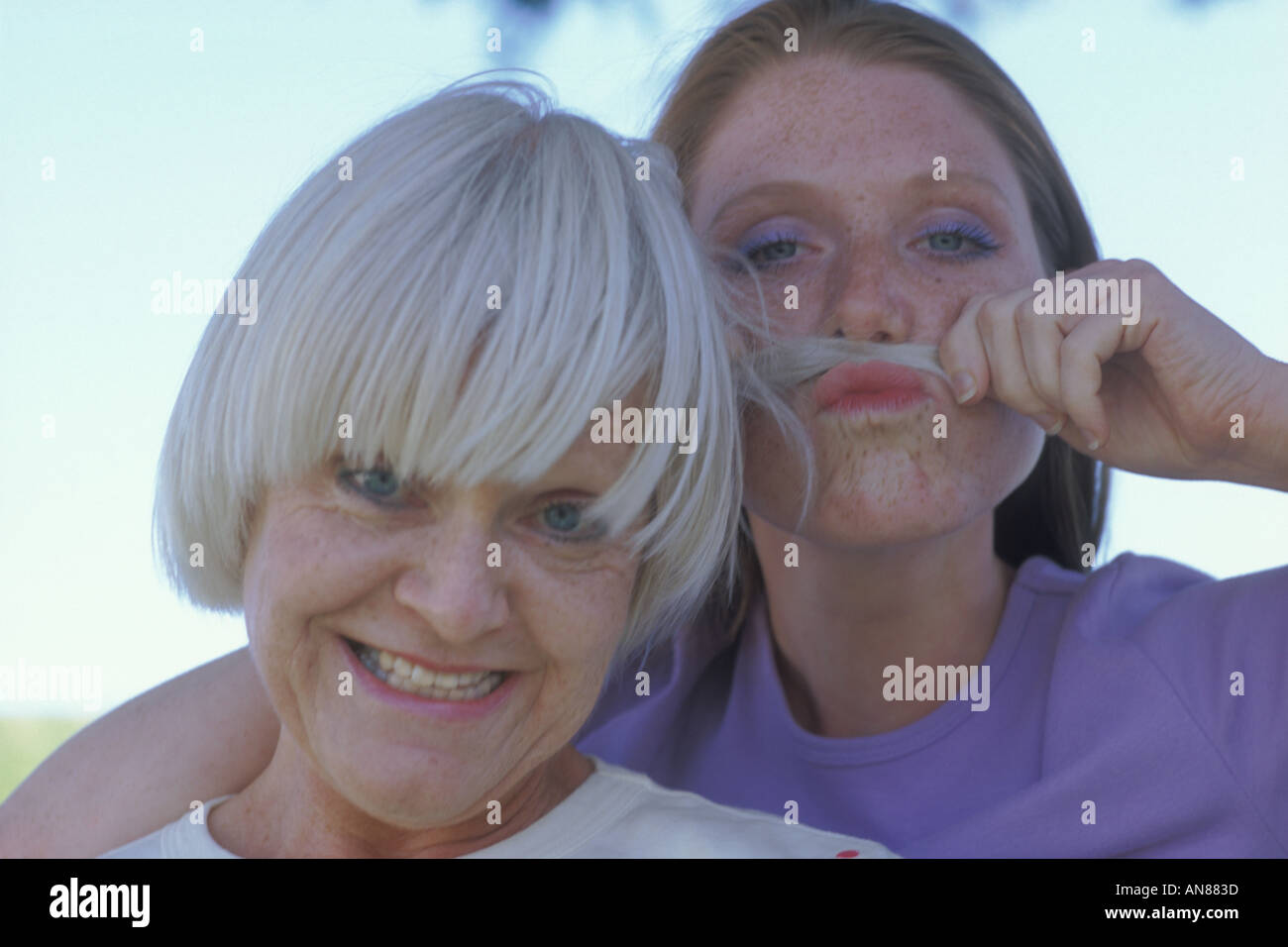 Portrait of 57 year old Caucasian woman with 22 year old daughter who is making a 'fake moustache' with her mother s hair Stock Photo