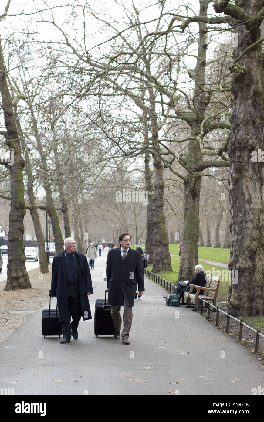 Two men pull suitcases along a footpath in St James' Park, Westminster, London, UK. Stock Photo