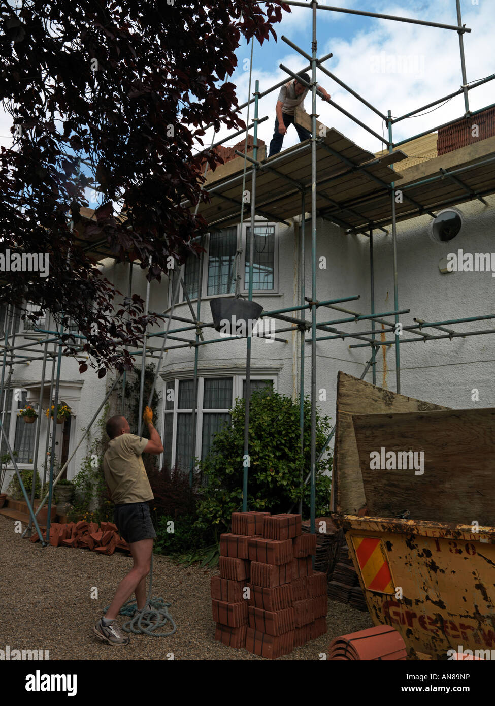 Builders using a Hoist to lift tiles to the roof Stock Photo