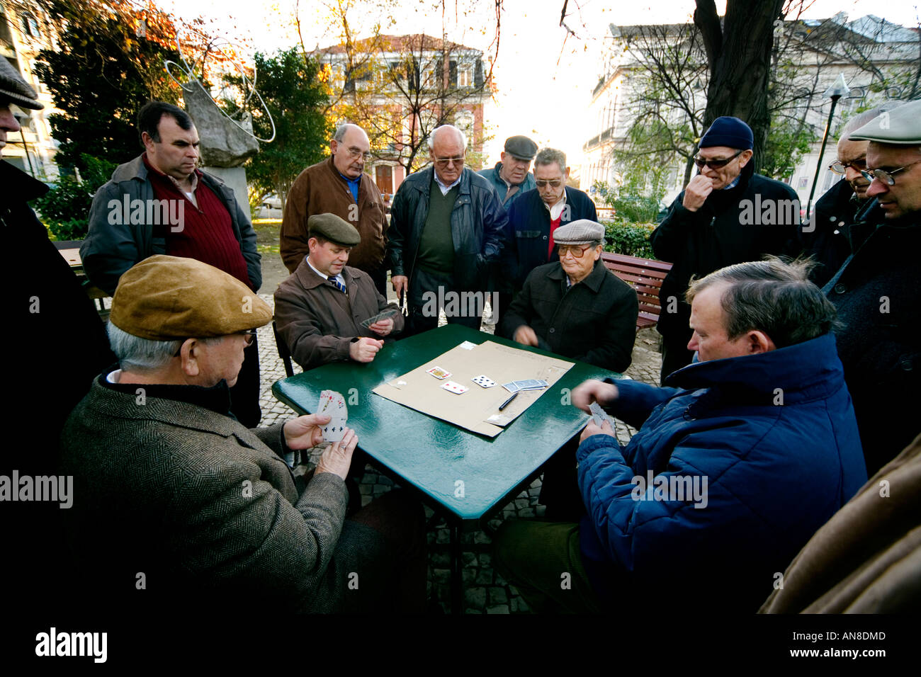 LISBON PORTUGAL Men play cards in Parque Mayer as others watch Stock Photo