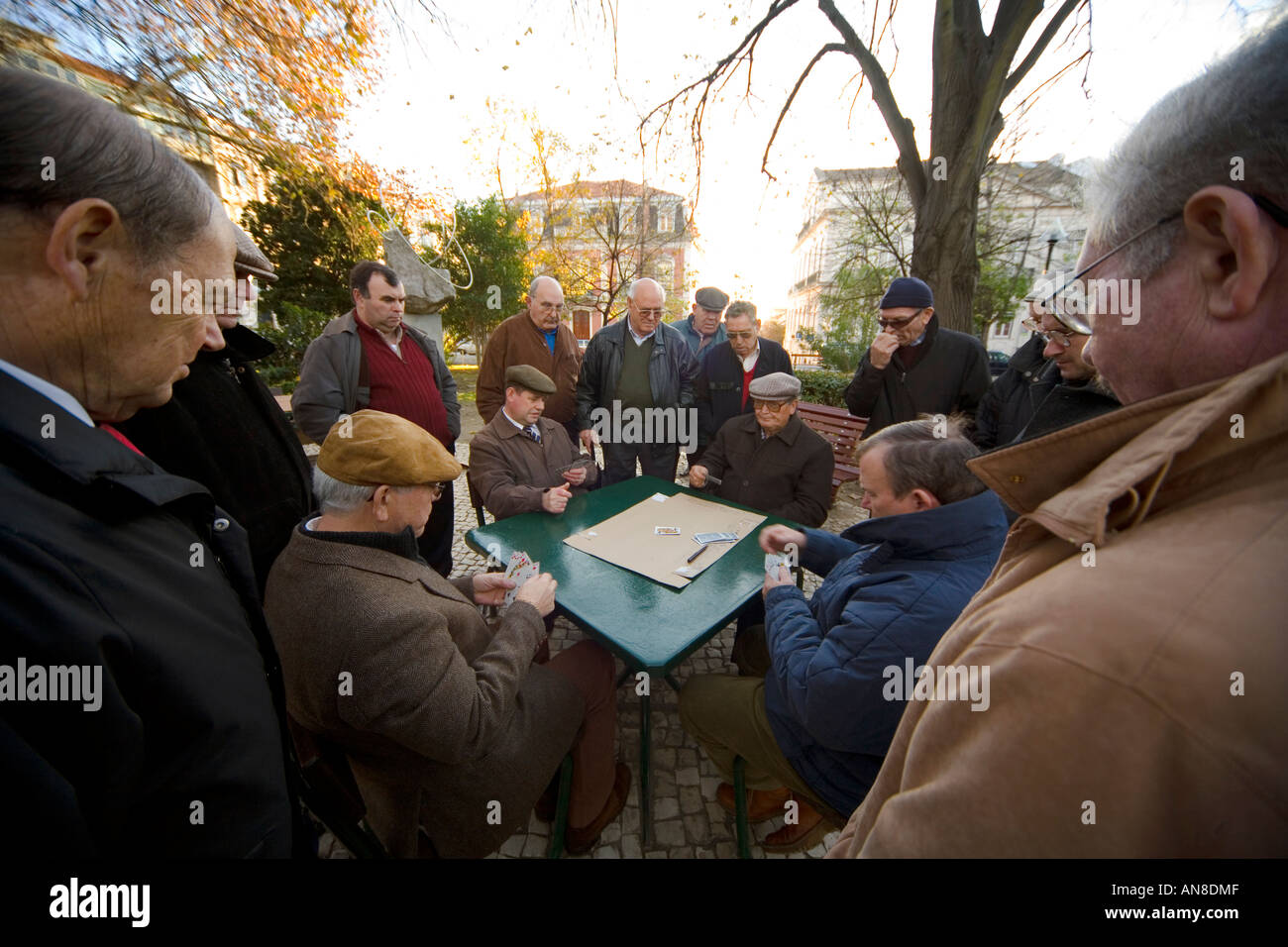 LISBON PORTUGAL Men play cards in Parque Mayer as others watch Stock Photo