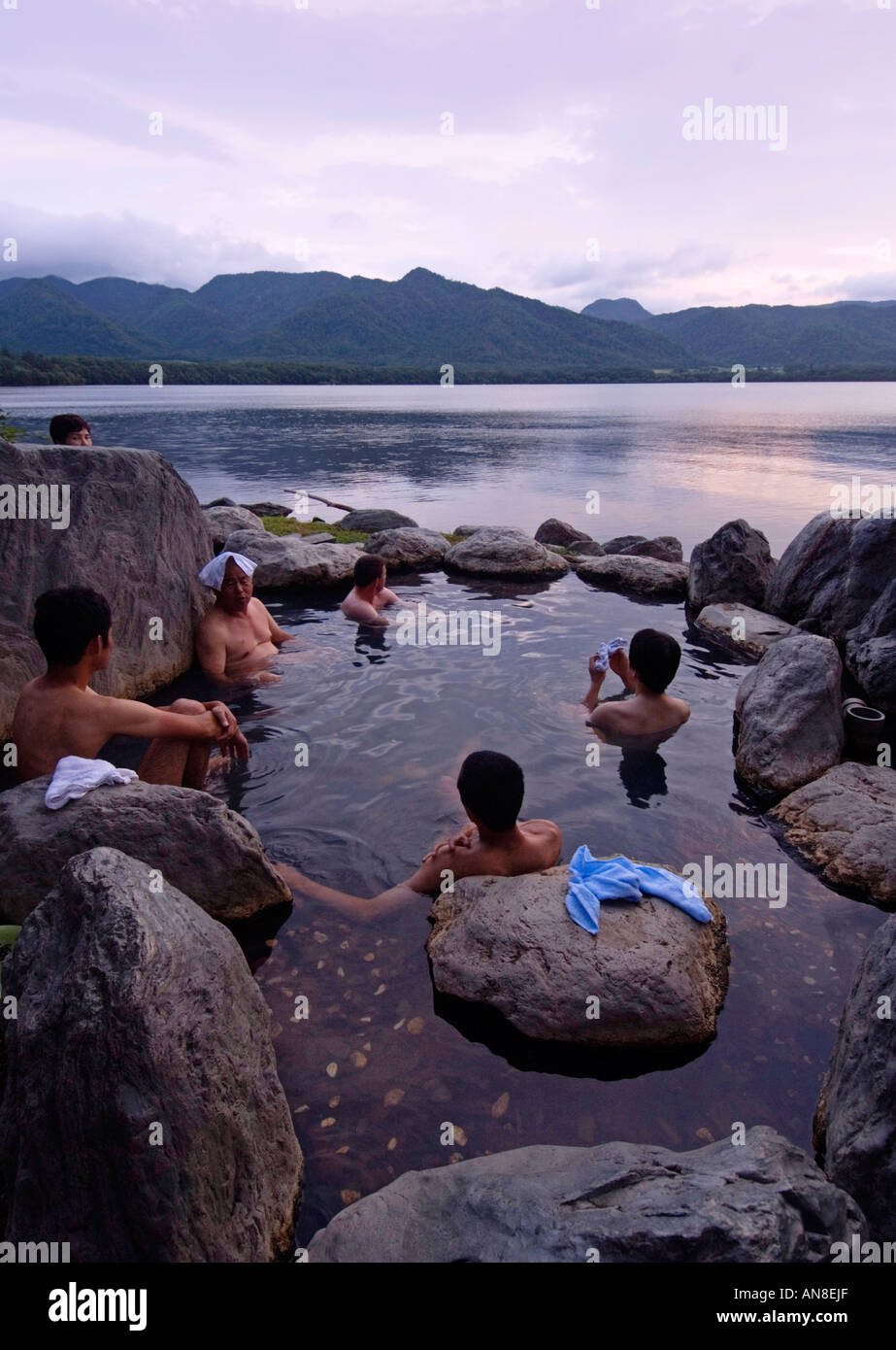 People bathing in evening in public outdoor rotemburo onsen on shore of Lake Akan in Akan National Park Hokkaido Japan Stock Photo