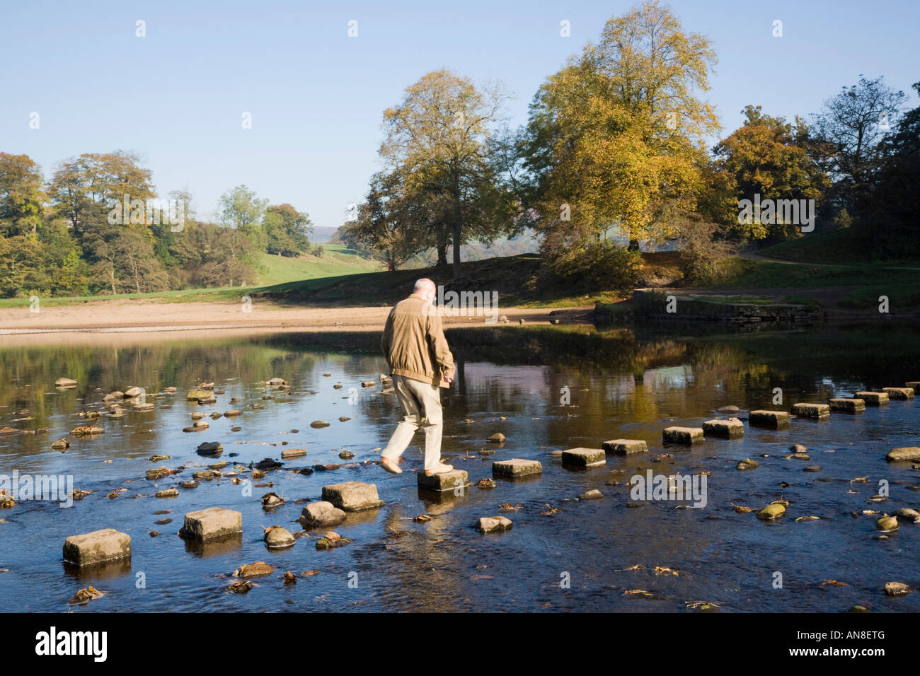 Person walking on stepping stones across River Wharfe in Yorkshire Dales National Park. Bolton Abbey Wharfedale Yorkshire England UK Stock Photo