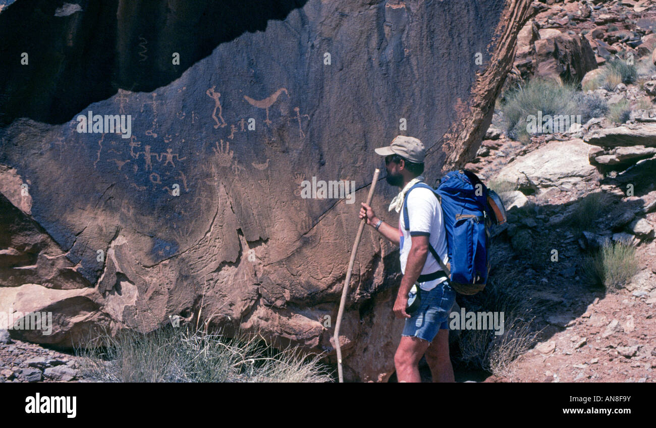 A hiker examines Anasazi petroglyphs on sandstone on cedar mesa along the san juan River Stock Photo