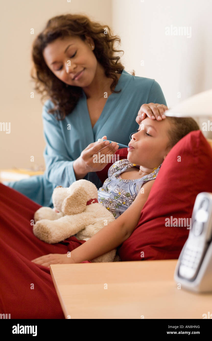 African mother taking daughter’s temperature Stock Photo