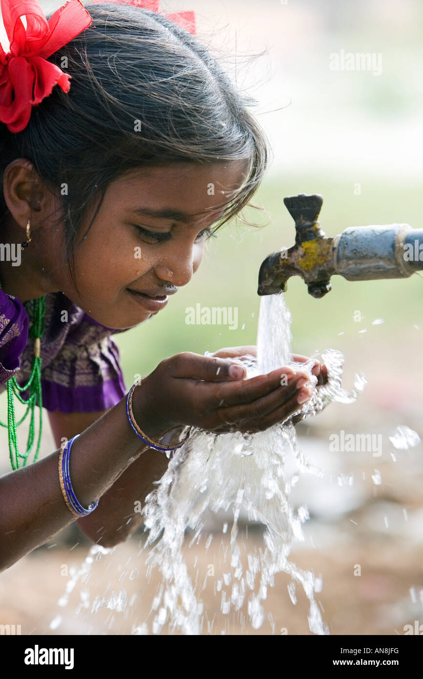 Indian girl drinking from a communal water tap. Puttaparthi, Andhra