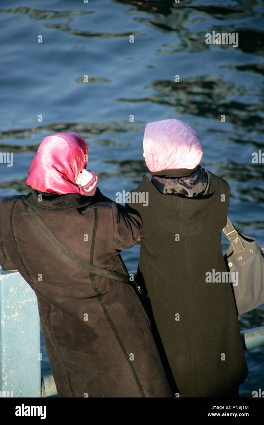 Two headscarfed girls, Istanbul, Turkey, one using a mobile phone Stock Photo