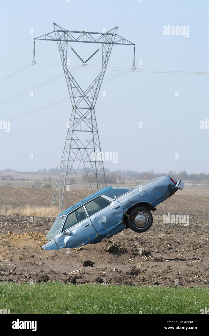 Car sticking out of ground near electrical transmission lines in Iowa Stock Photo