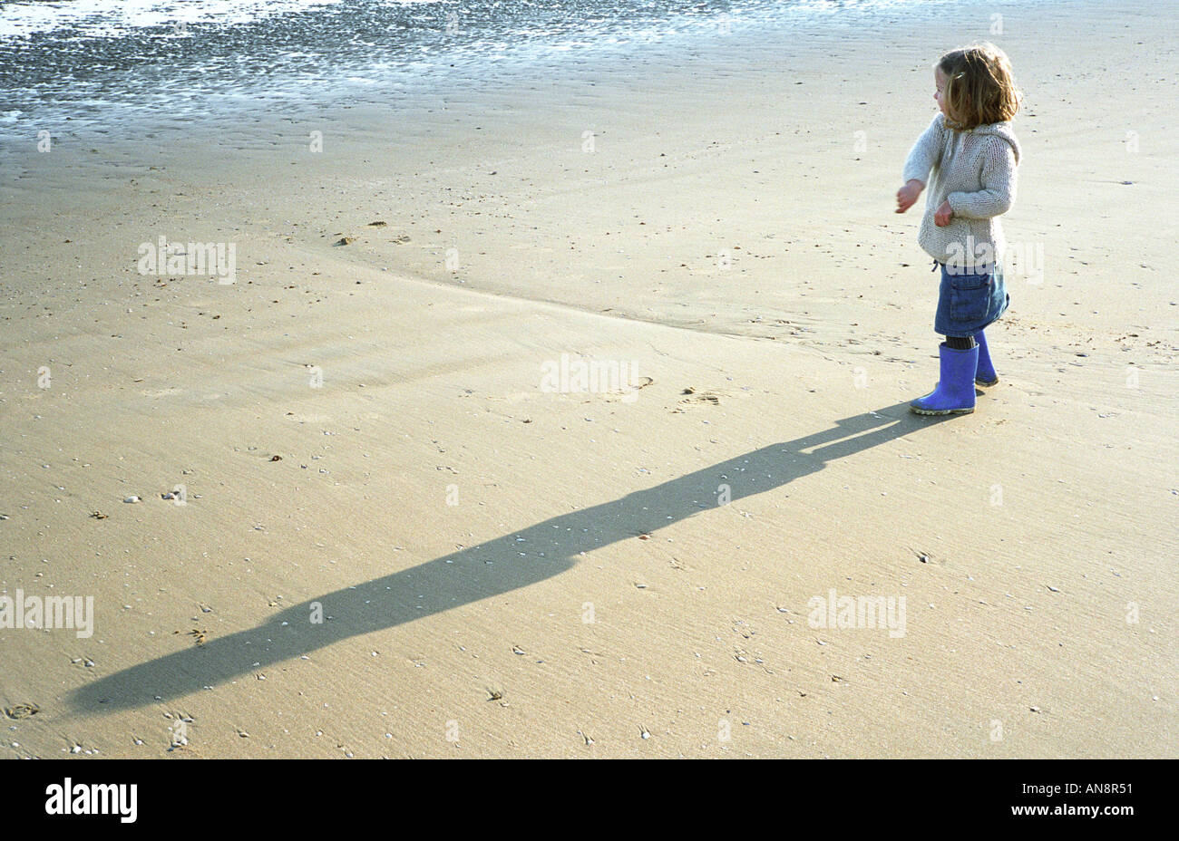 little girl thowing stone into sea Stock Photo