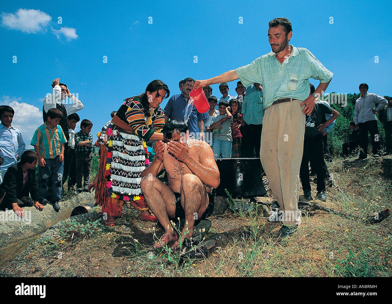Traditional pre wedding bath of groom by sister of bride and friends