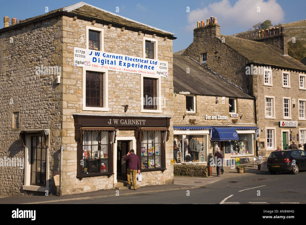 Shops in traditional limestone buildings in historic town centre with incongruous sign Settle Yorkshire UK Stock Photo