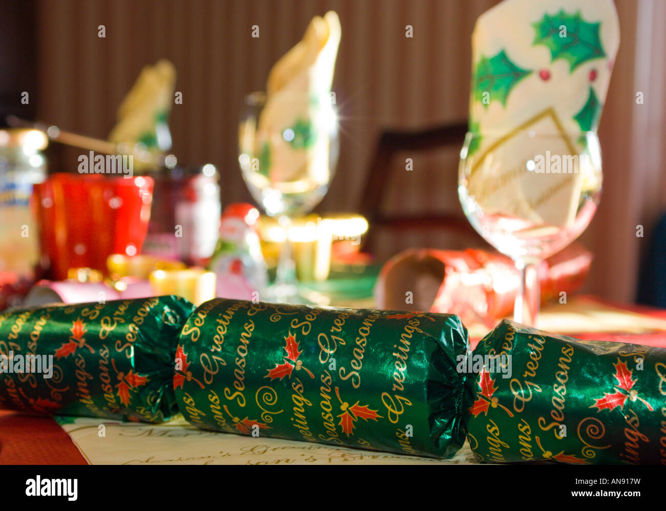 Christmas cracker on table with wine glasses and napkins in background Stock Photo