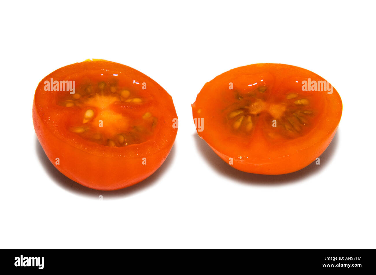 Two cherry tomato halves, baby tomato, against white background. Stock Photo