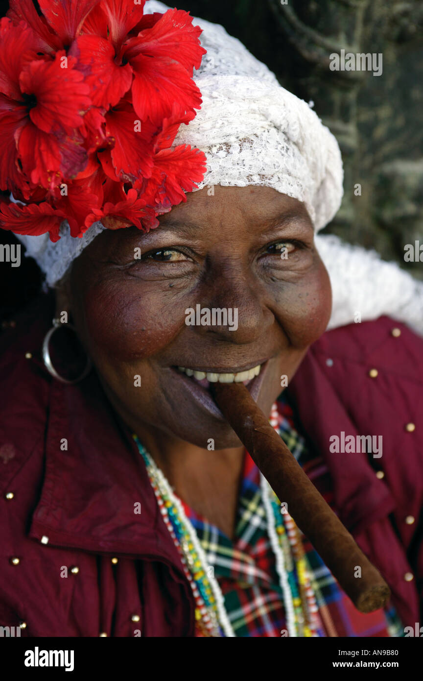 A Cuban lady dressed in traditional costume smokes a cigar. Stock Photo