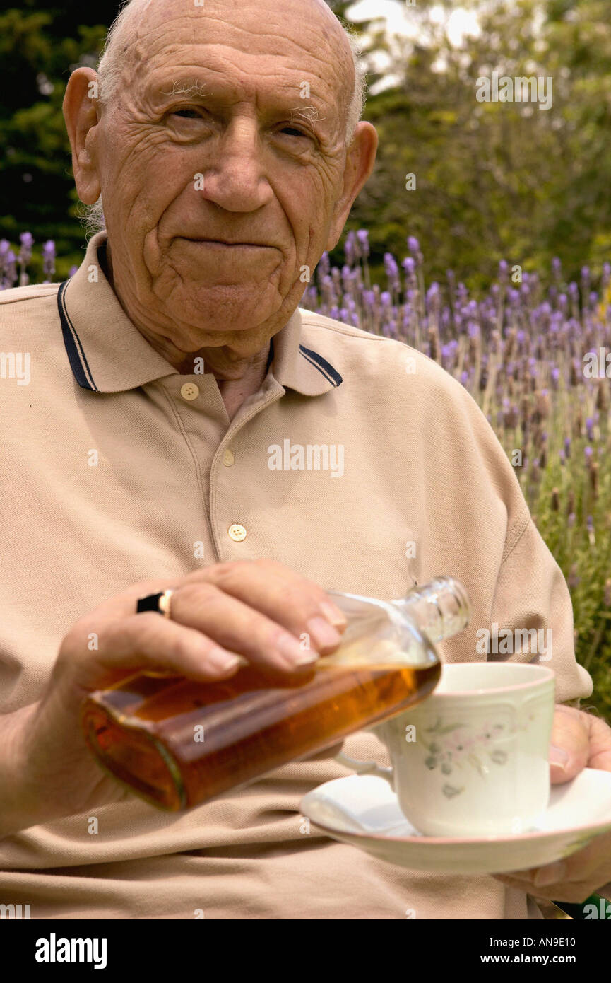 A senior man pouring alcohol into his teacup Stock Photo Alamy