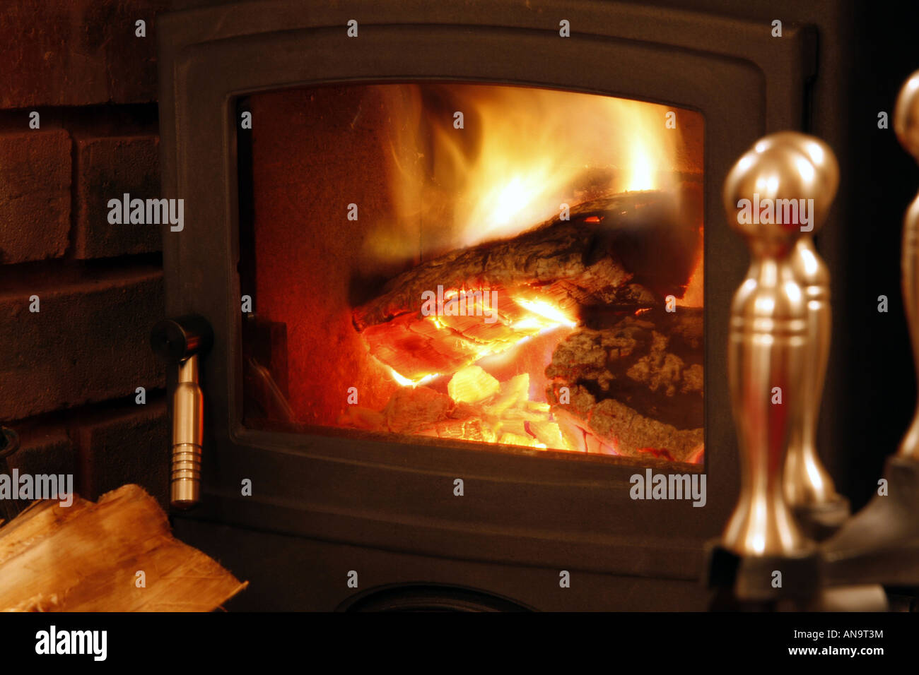 Out of focus fire irons in front of a blazing cast iron log burner fire