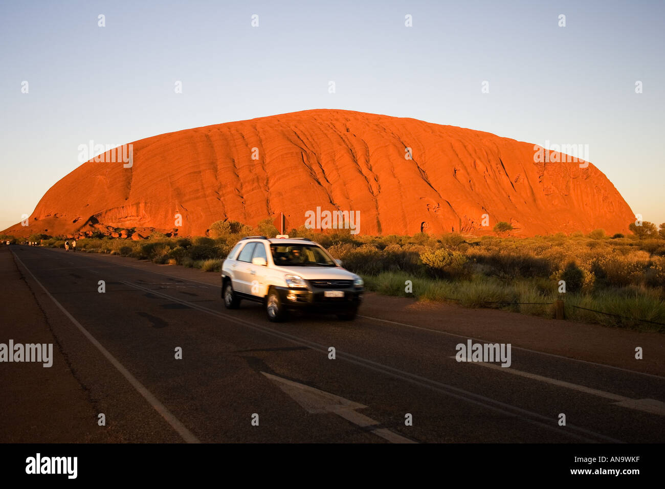 Car drives past Ayers Rock Uluru Red Centre Australia Stock Photo