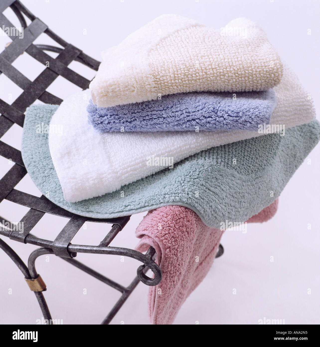 Close Up Of Pale Blue And Pink Bath Mats On Metal Chair Stock