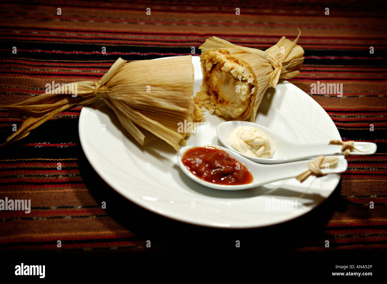 Mexican tamal cut in half served on plate with salsa Stock Photo