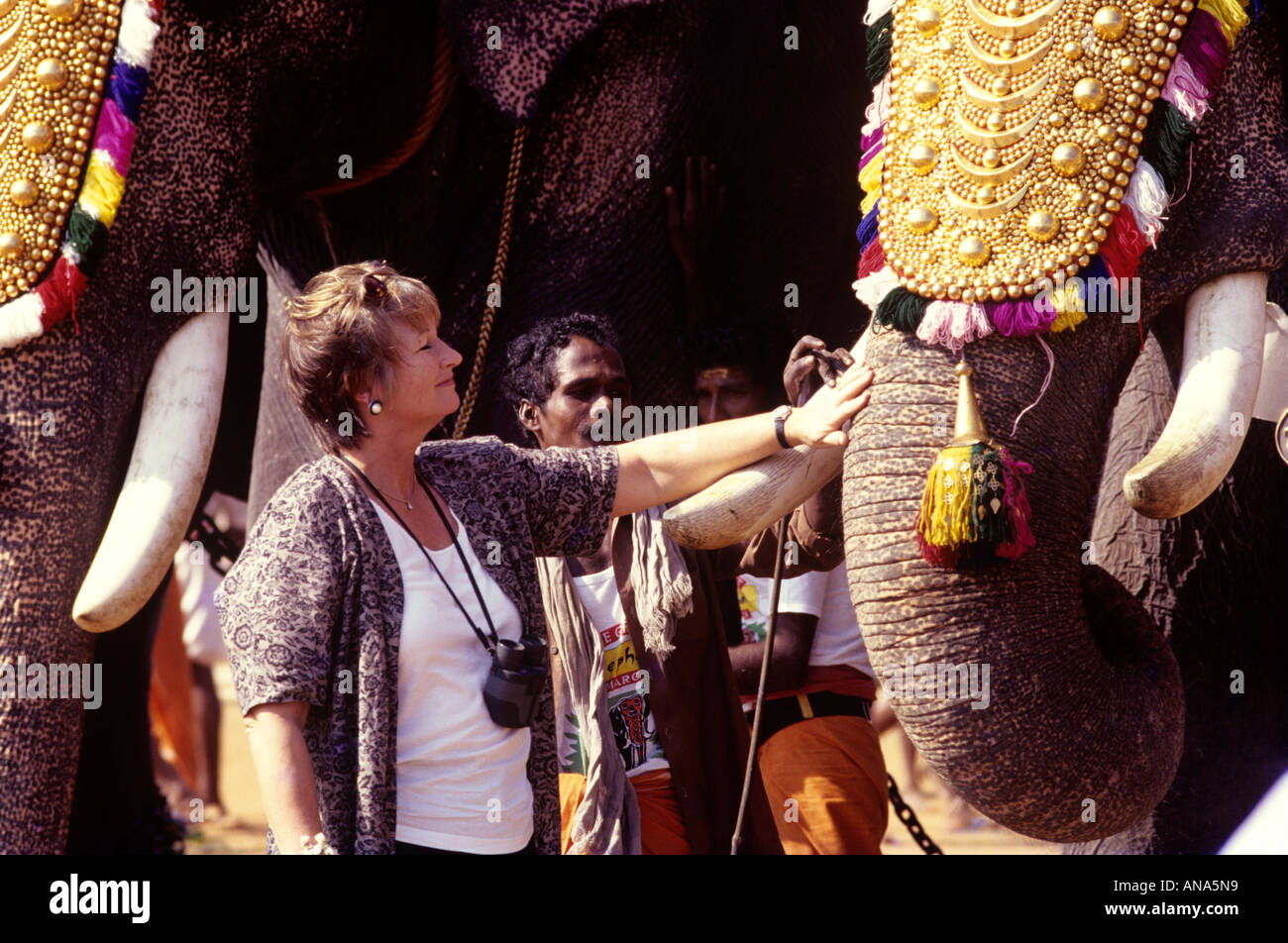 A TOURIST NEAR A CAPARISONED ELEPHANT IN THRISSUR KERALA Stock Photo