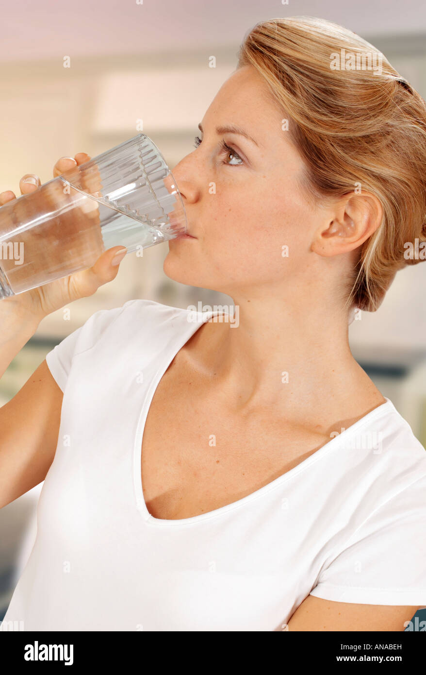 WOMAN IN KITCHEN DRINKING WATER Stock Photo