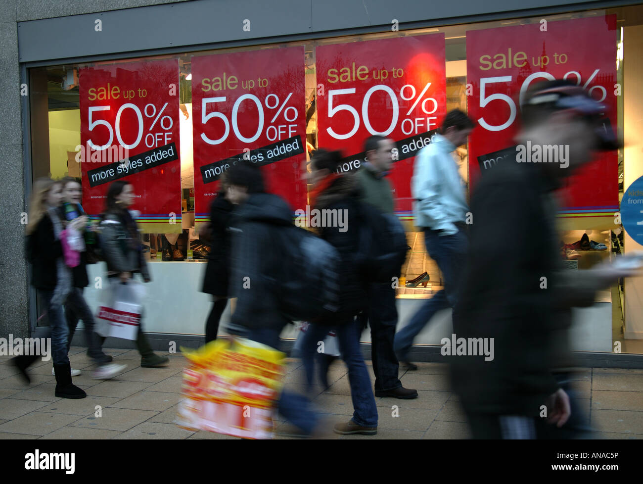 Shop window sale signs with passing blurred pedestrians in the foreground, Edinburgh, Scotland Stock Photo
