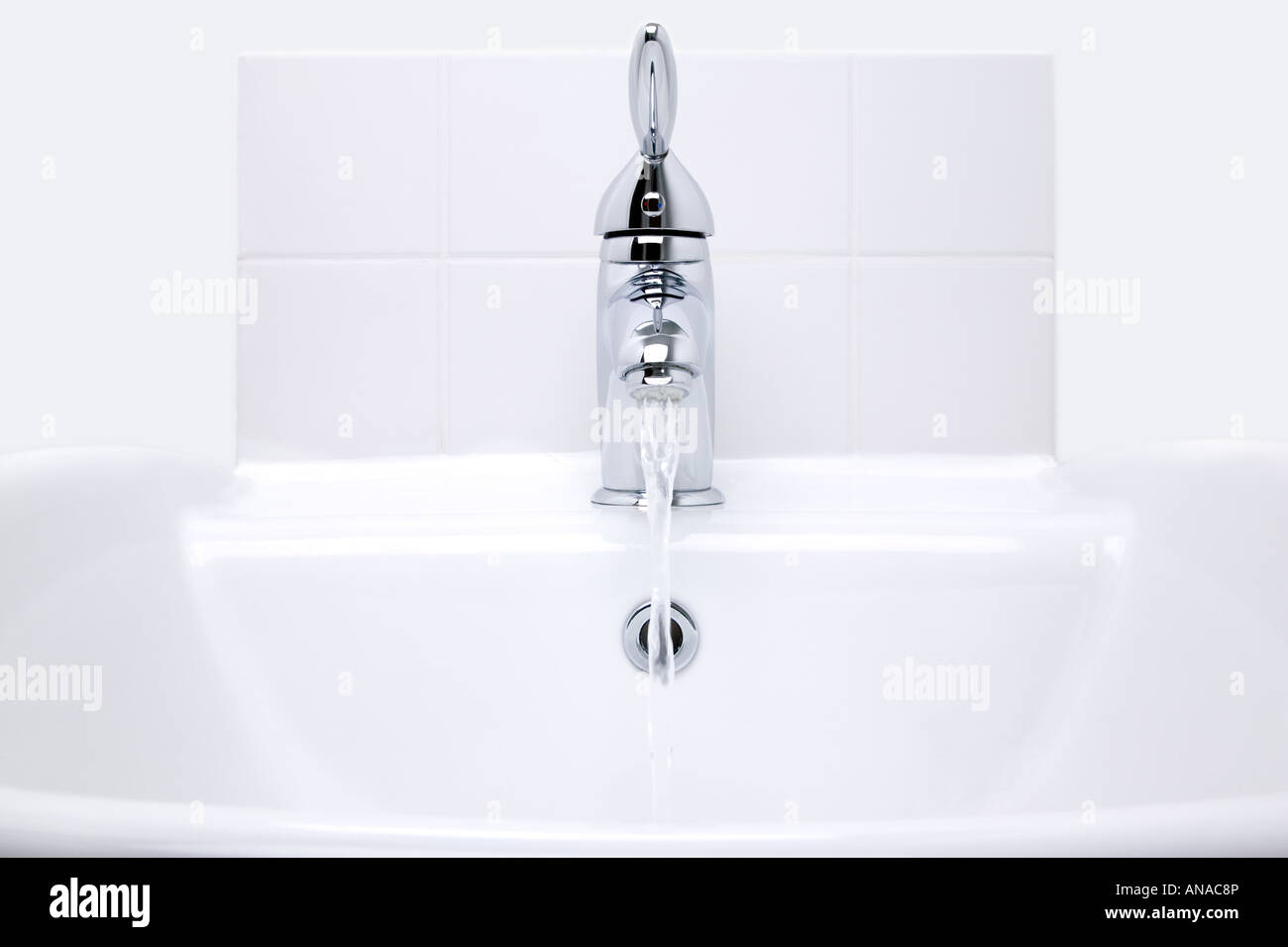 White modern ceramic handbasin and chrome tap water running Stock Photo