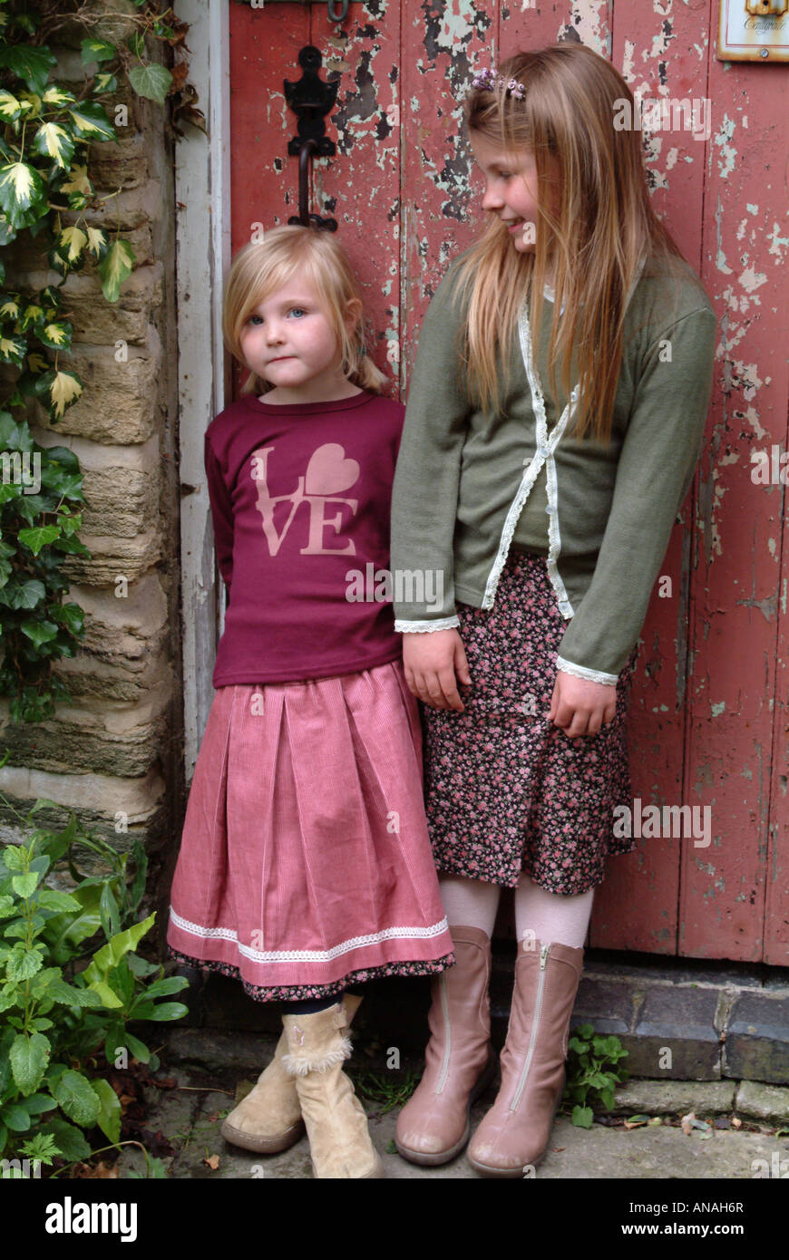 Portrait of two girls standing in front of a door Stock Photo - Alamy