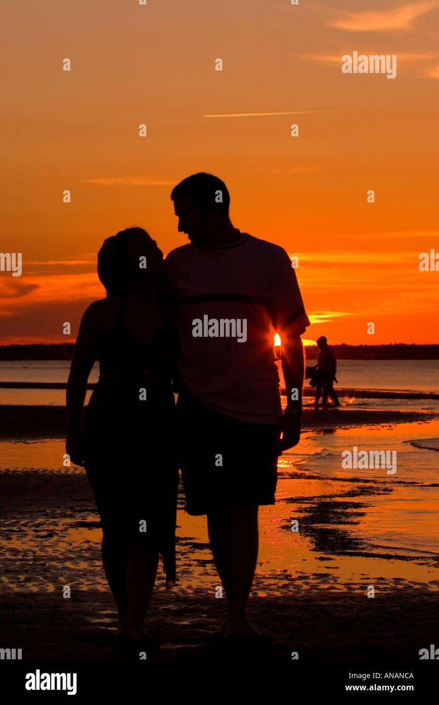 Silhouette of young couple walking on beach at sunset Stock Photo - Alamy