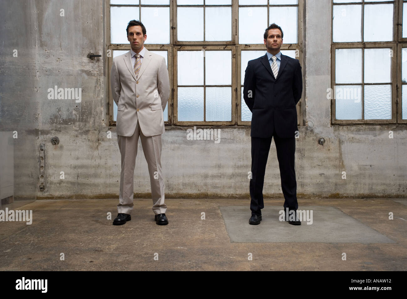portrait of two businessmen standing side by side in empty building ...