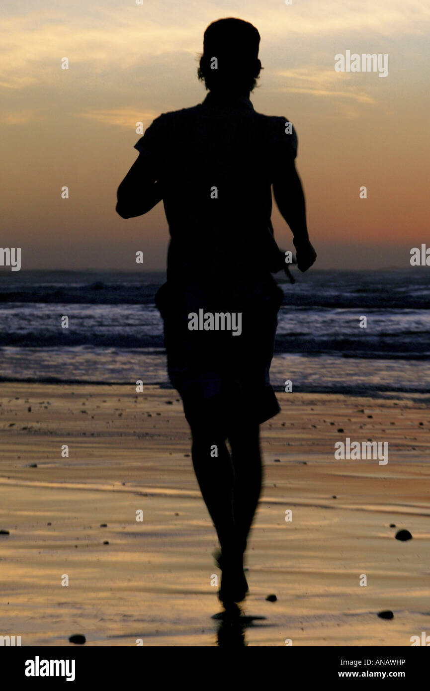 silhouette of a joung man jogging at the beach, New Zealand Stock Photo