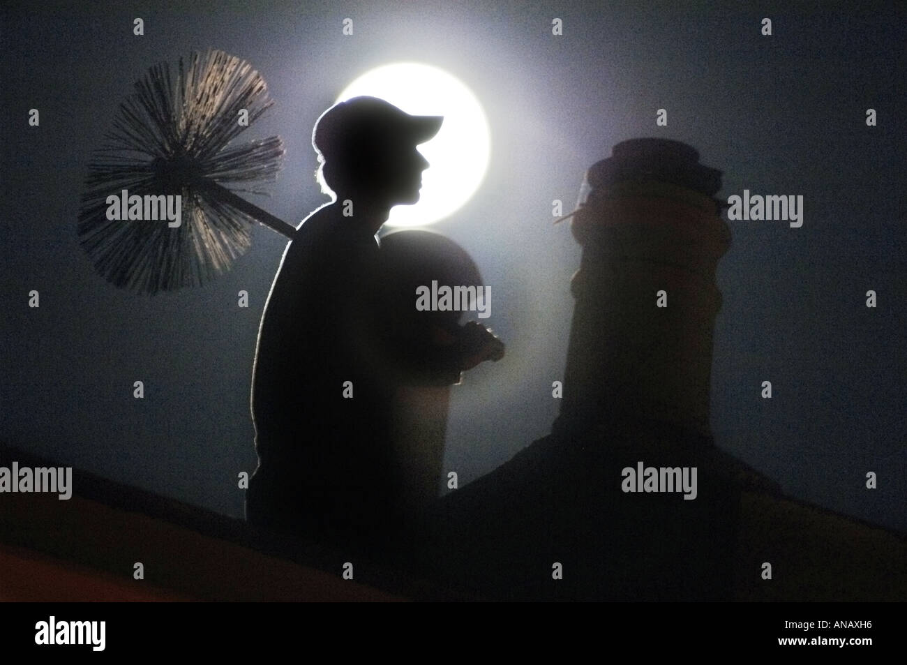 A young chimney sweep sits and dreams on a rooftop in Brighton by the light of a full moon Stock Photo