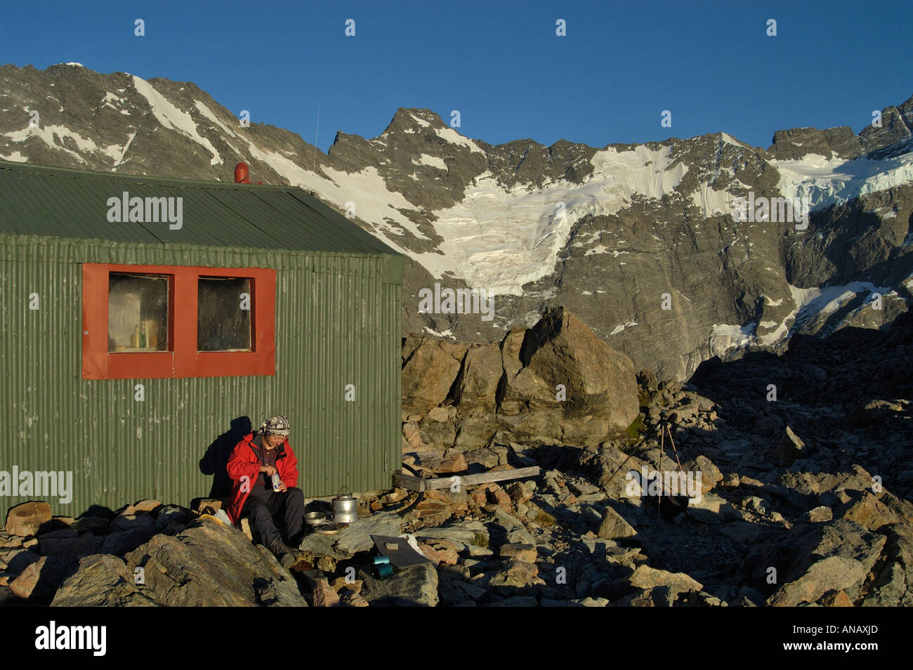 Hiker sits in the evening sun at the old Mueller hut, Mount Cook Nationalpark, South Island, New Zealand Stock Photo