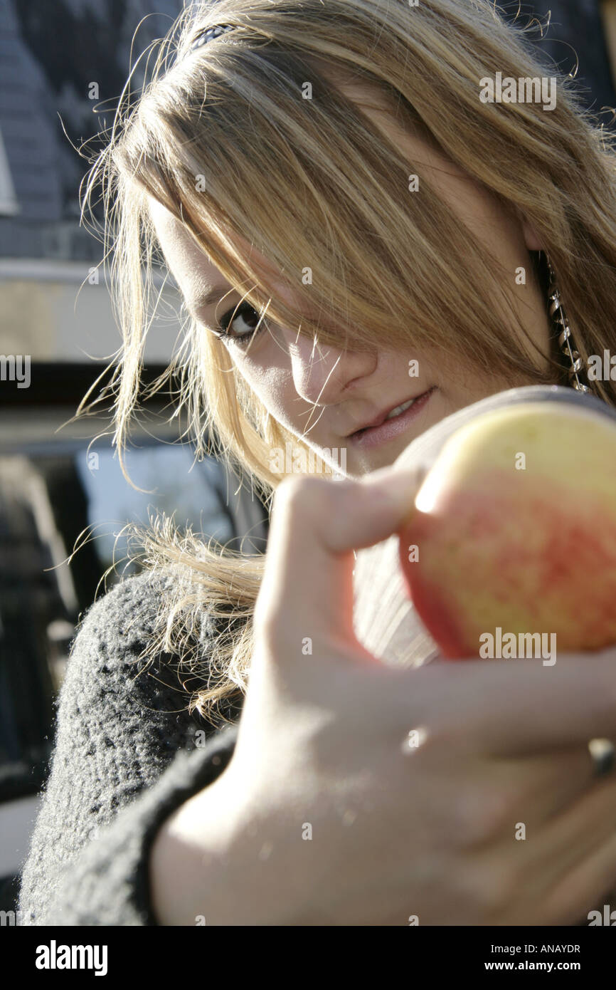 young pretty female model holding an apple into the camera Stock Photo