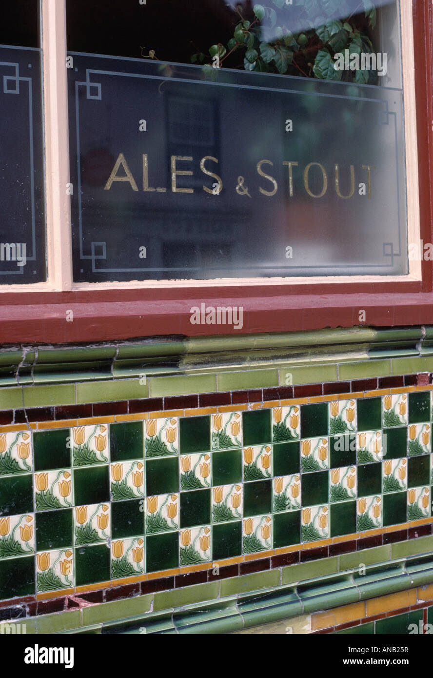 Engraved glass window above green patterned Victorian tiles on exterior wall of Public House Stock Photo