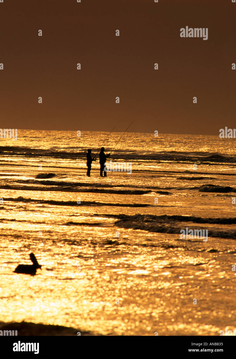 NC Outer Banks Silhouettes of fishermen on a sandbar in golden light Stock Photo