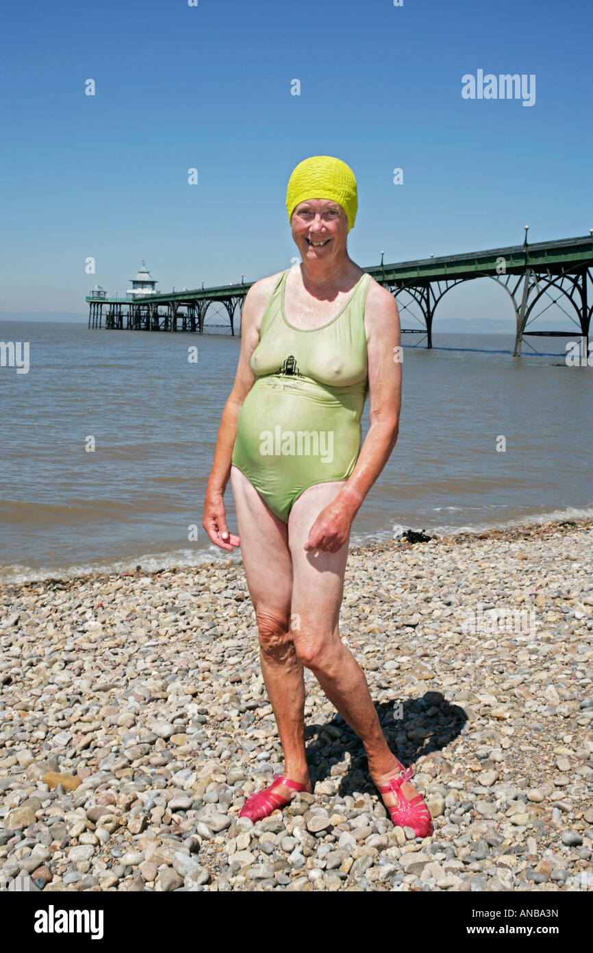 Old lady in bathing costume and swimming hat on pebbled beach in ffront of  pier on the Bristol channel Stock Photo - Alamy