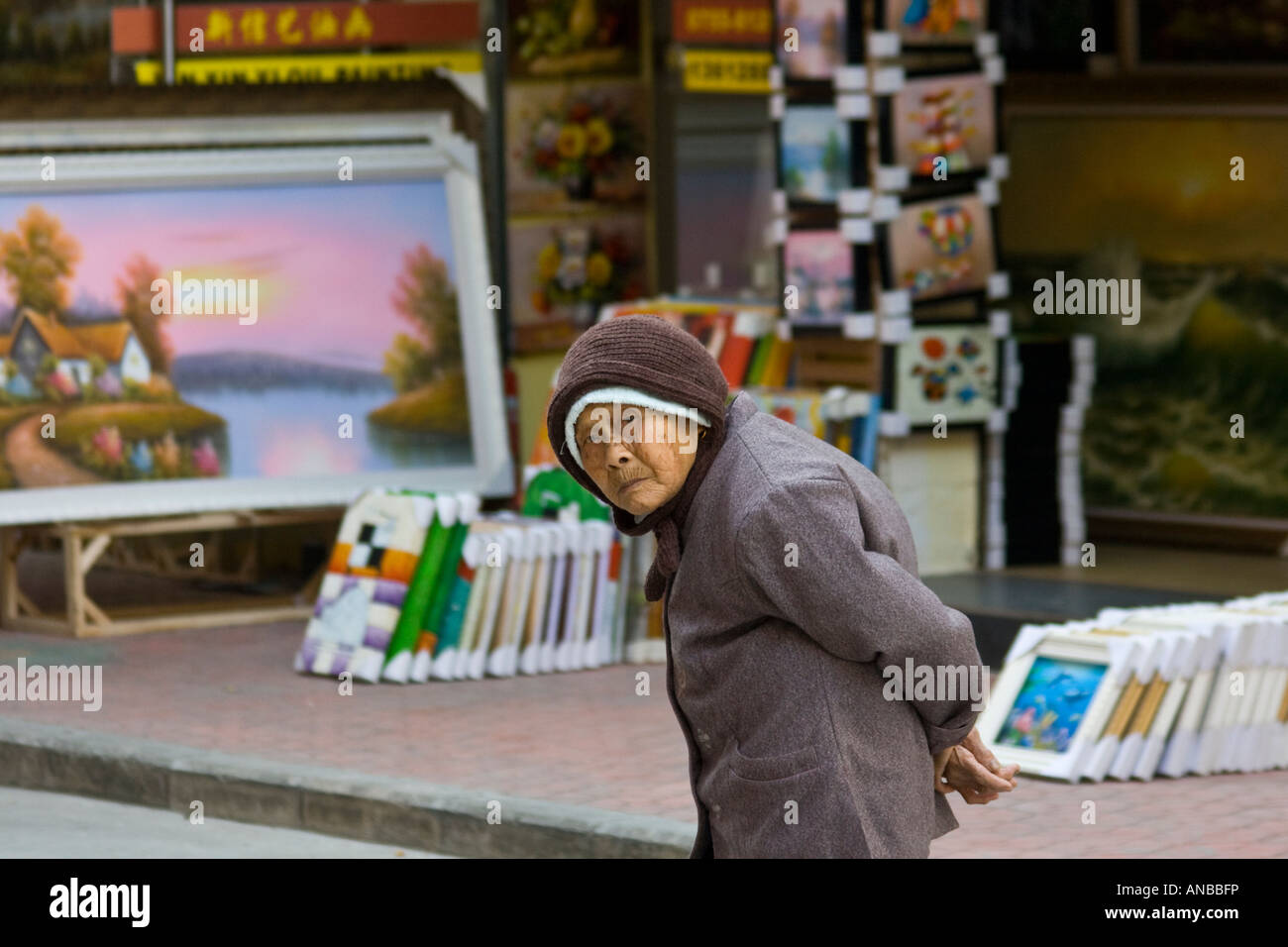 Elderly Chinese Woman and Oil Paintings at an Art Gallery Da Fen Painting Village Shenzhen China Stock Photo