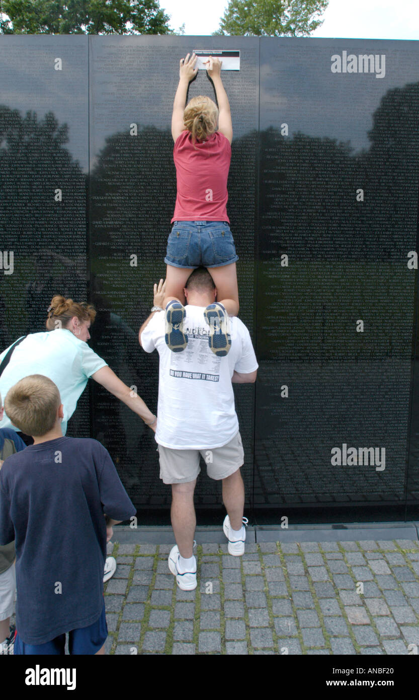 Taking rubbings of the names of those killed in Asia, from the Vietnam Memorial Wall in Washington D C boy standing on dad's shoulders Stock Photo