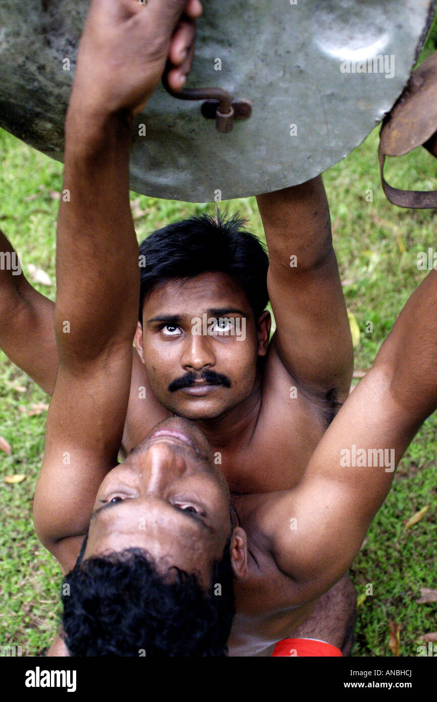 Two men practice the ancient martial art of Kalarippayattu in Kerala, India. They lock shields. Stock Photo