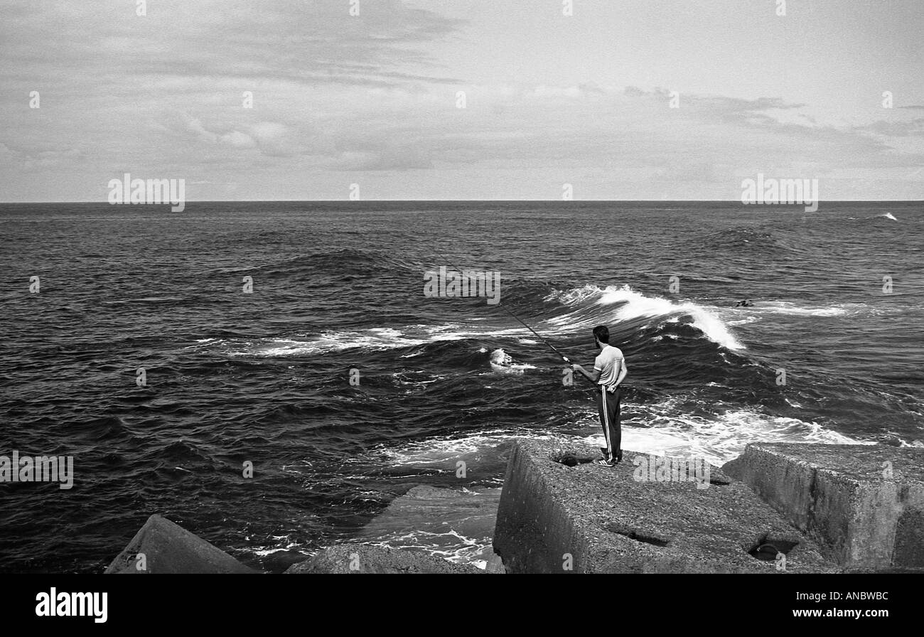 Man fishing in Atlantic ocean from man made breakwater on the north coast of Tenerife Stock Photo