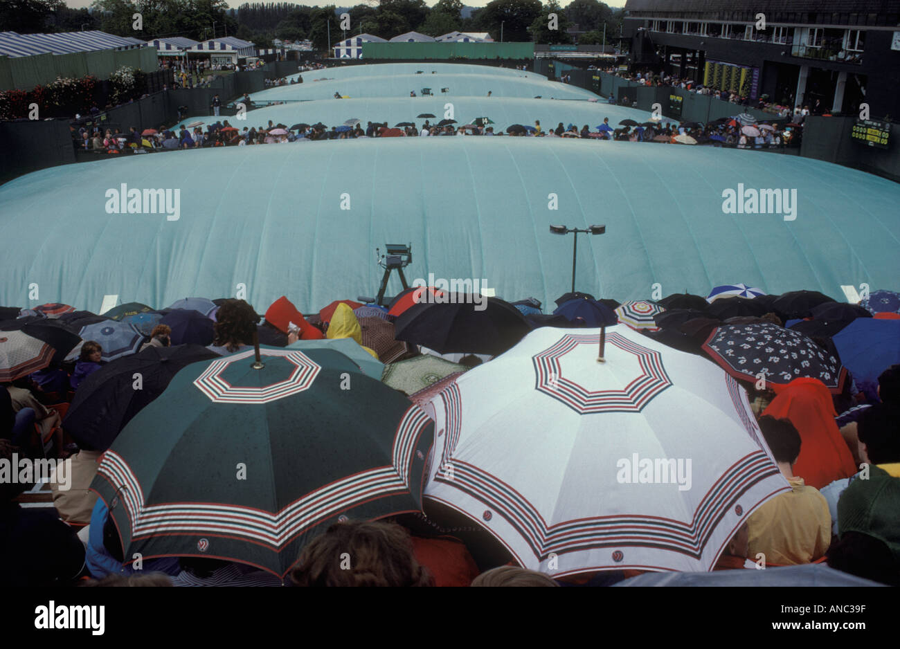 Wimbledon rain covers over courts, fans wait for bad weather to improve. Rain stops play Wimbledon tennis London SW19 1980s UK. 1985 HOMER SYKES Stock Photo