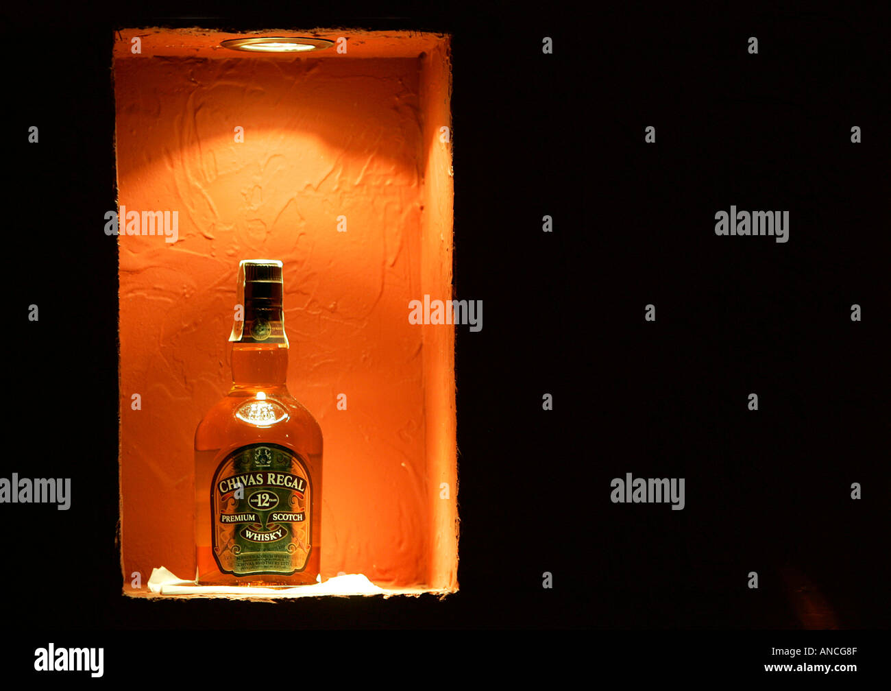 Chivas Regal whisky premium scotch 12 years old alcohol beverage Night bar restaurant beach orange light dark alone one bottle d Stock Photo