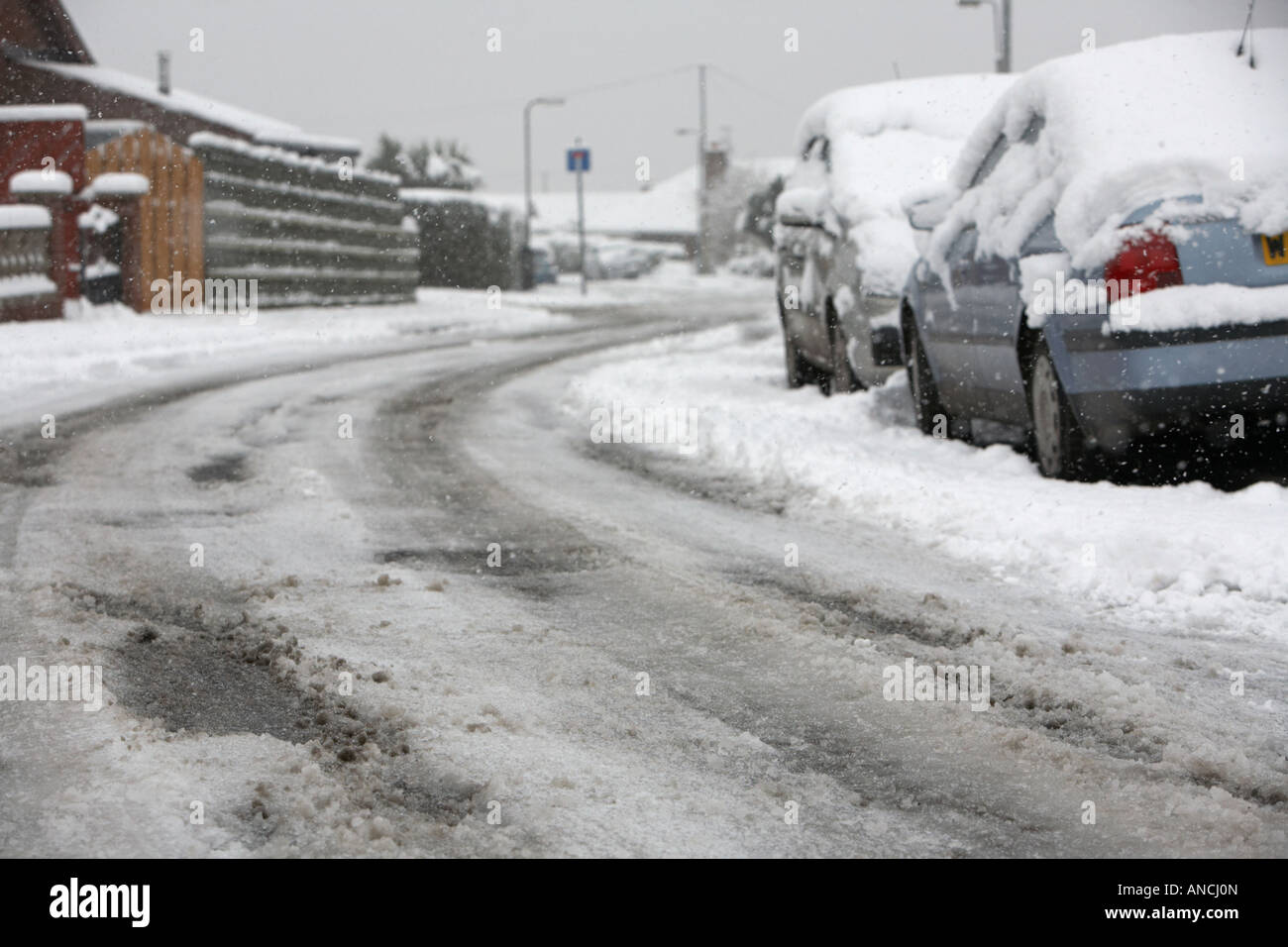 tyre tracks and car marks in the middle of the road on bend of snow covered street with ice