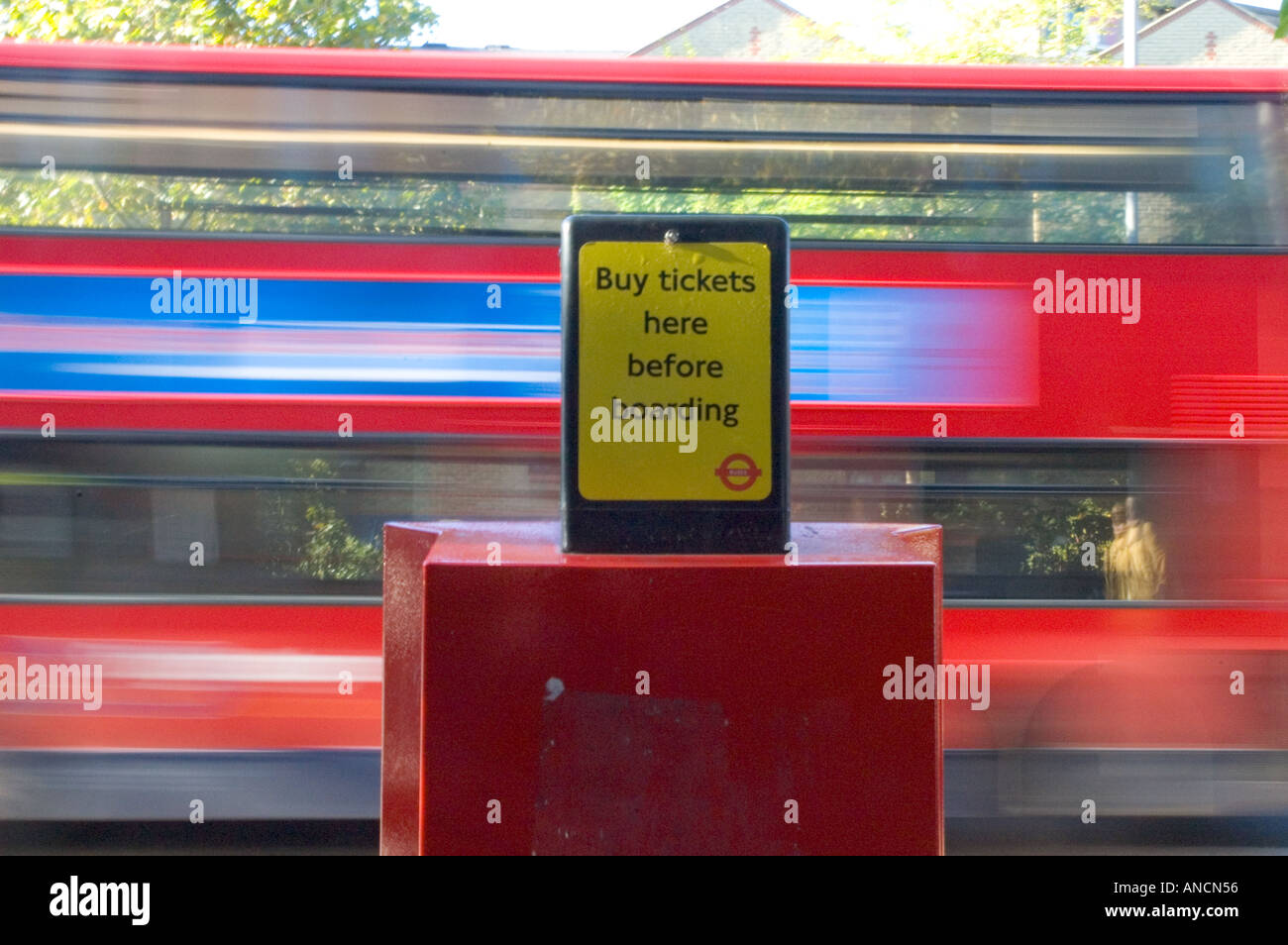 Bus ticket machine in the foreground with a blurred affect speeding bus in the background. Stock Photo