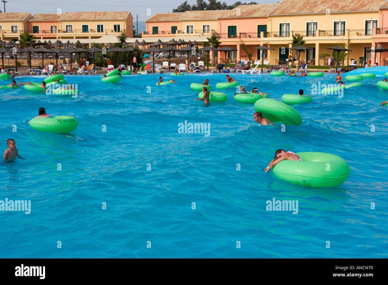People relax in the wave pool on floating tubes. Aqualand Water Park, Corfu island, Greece. Stock Photo