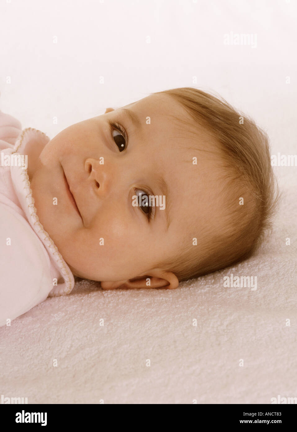 Happy baby girl lying down on her back smiling Stock Photo