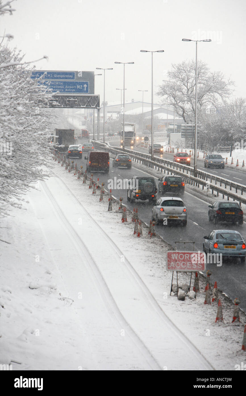 cars driving slowly along treated gritted motorway with works access ...