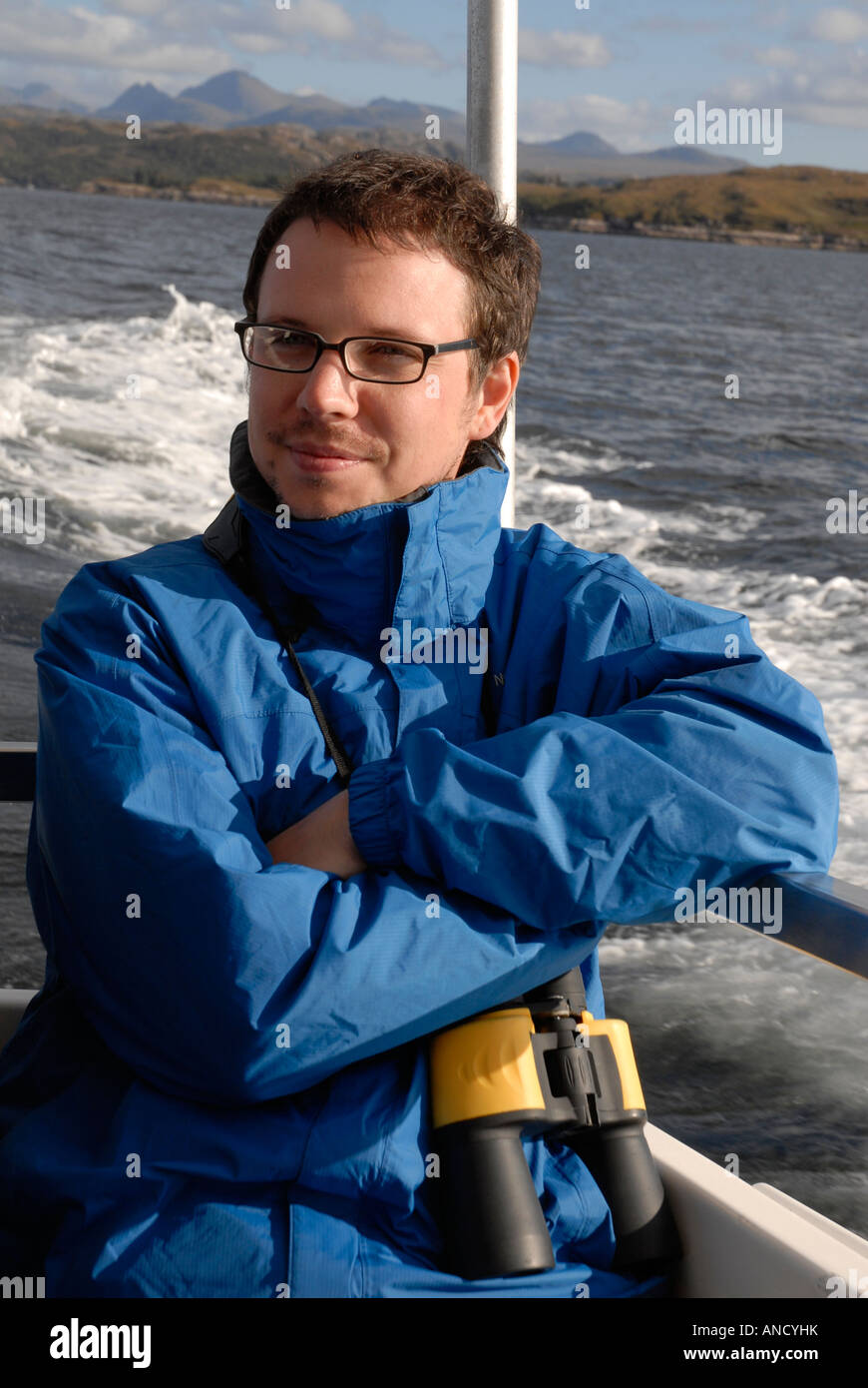 Portrait of a man standing on a boat with binoculars around his neck Stock Photo